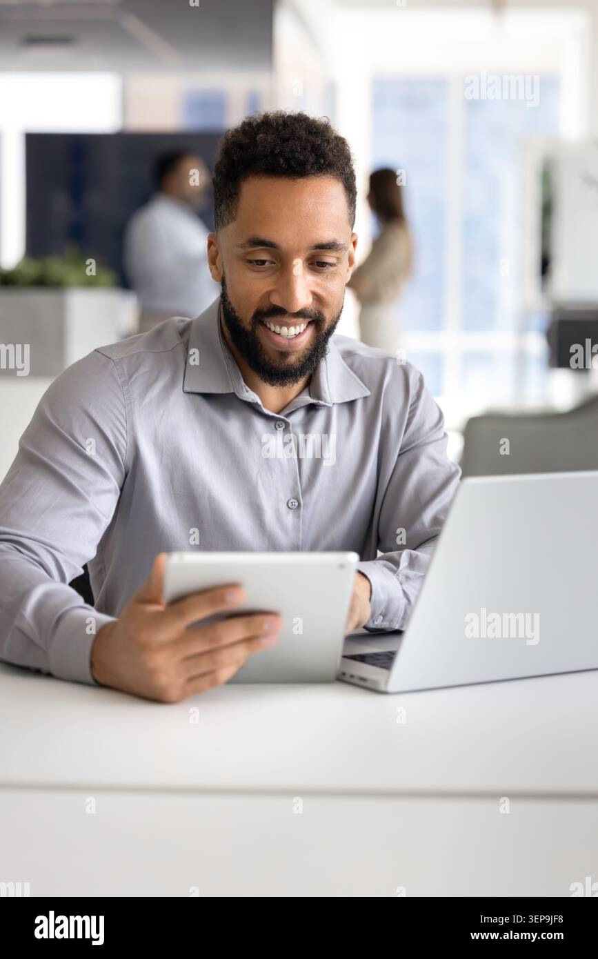 Smiling businessman using tablet at modern office desk Stock Photo