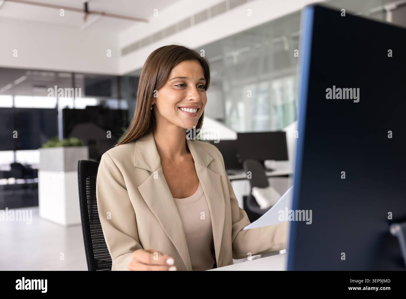 Smiling female office manager reading email or message on computer Stock Photo