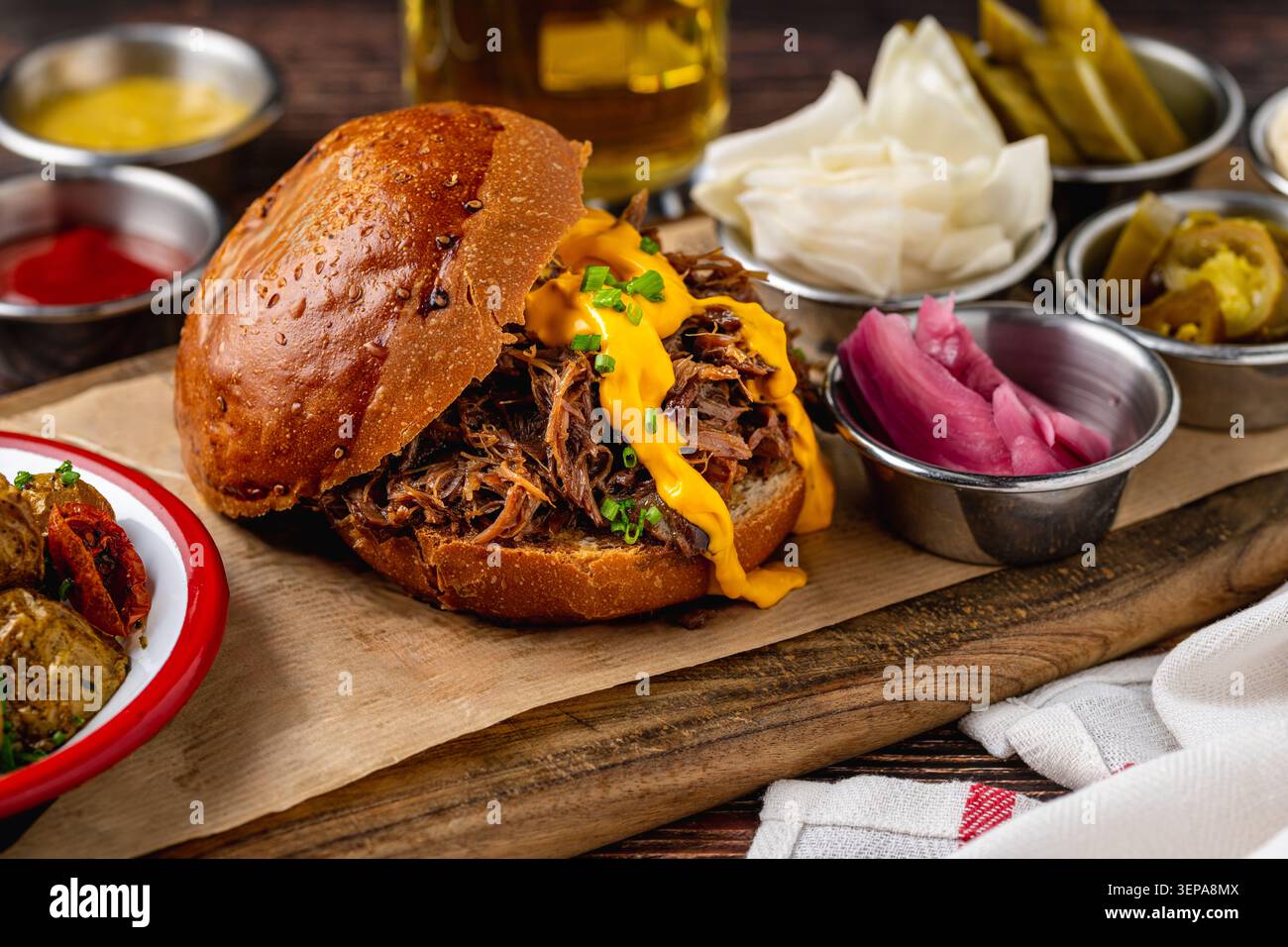 Slow cooked pulled rib beef burger with melted cheese and sides Stock Photo