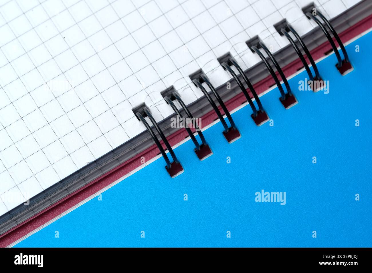 A checkered notebook lies open on a vibrant blue surface, waiting for creativity. Stock Photo