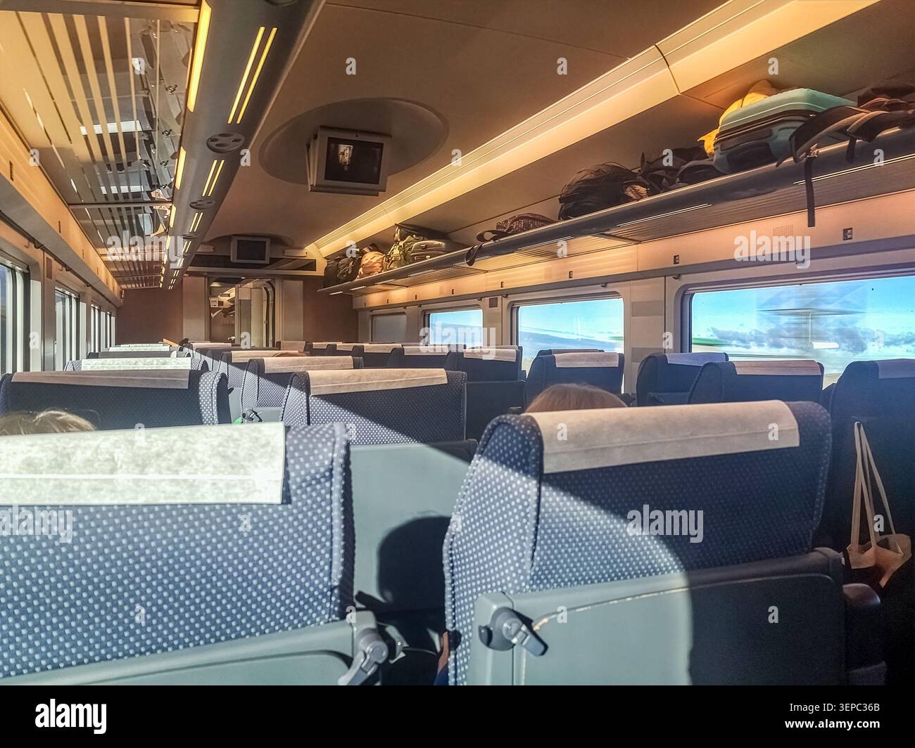 Interior of a modern high speed train with comfortable blue seats and luggage racks. Empty passenger car of a commute train moving through the country - Smartphone Captured Stock Image