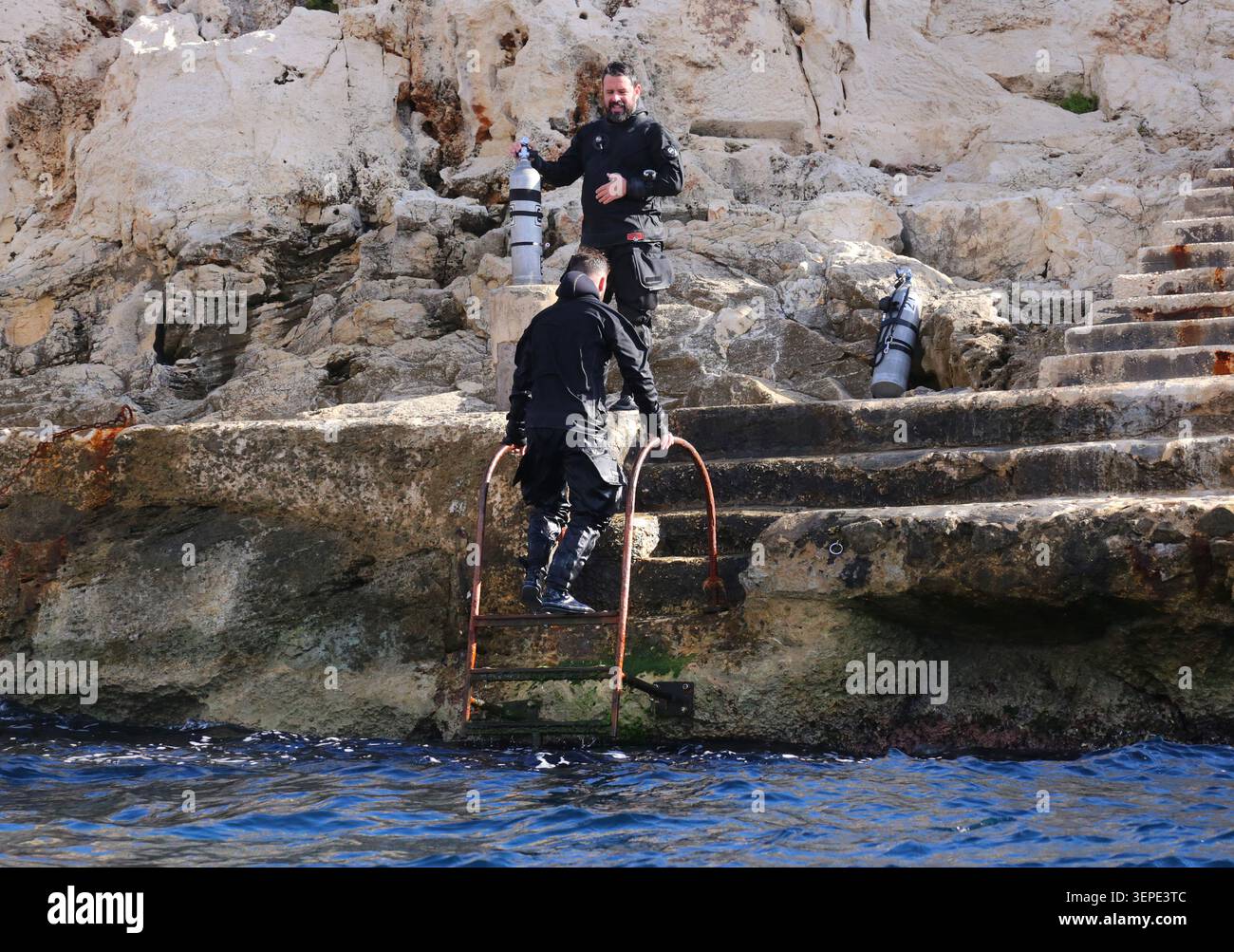 Wied iz-Zurrieq. Malta. Wied iz-Zurrieq, Malta - 12.22.2024: Scuba divers exiting water via a ladder after diving near Blue Grotto. Stock Photo