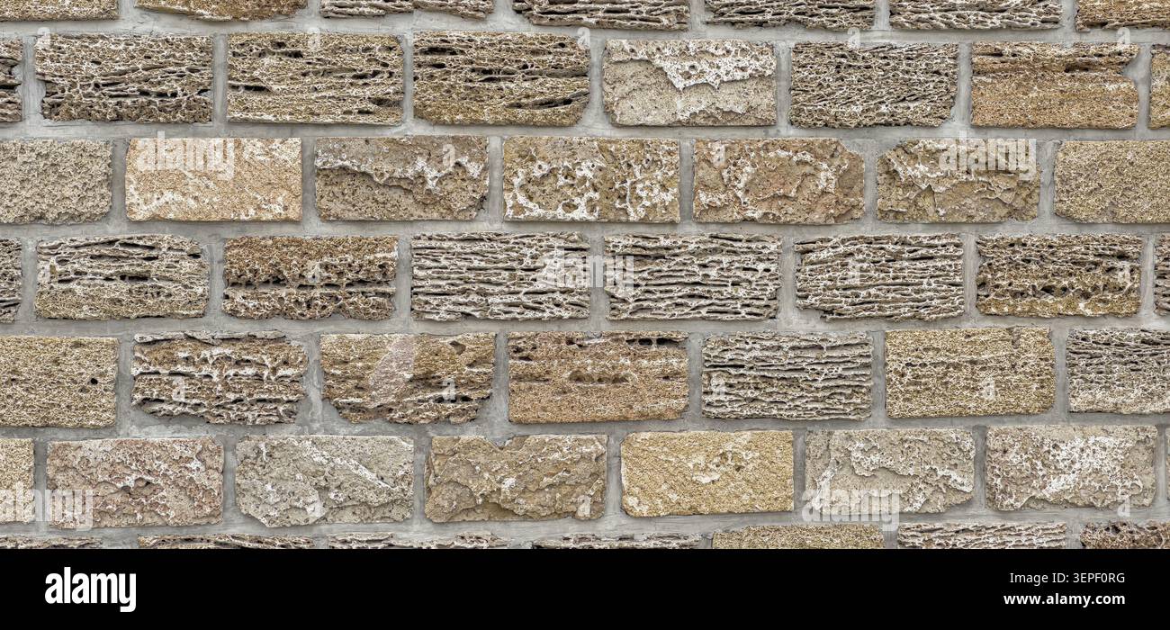 Porous limestone brick wall forming a rugged textured surface background Stock Photo