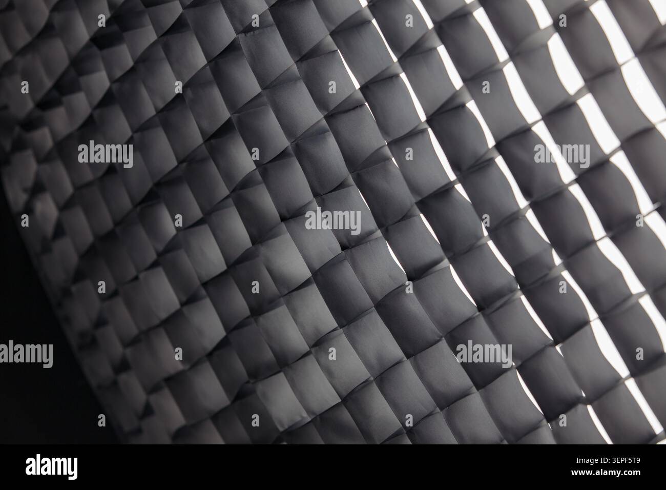 High-key macro photograph of a professional photographic honeycomb grid. The black mesh pattern is brightly and evenly illuminated, with all cells fil Stock Photo