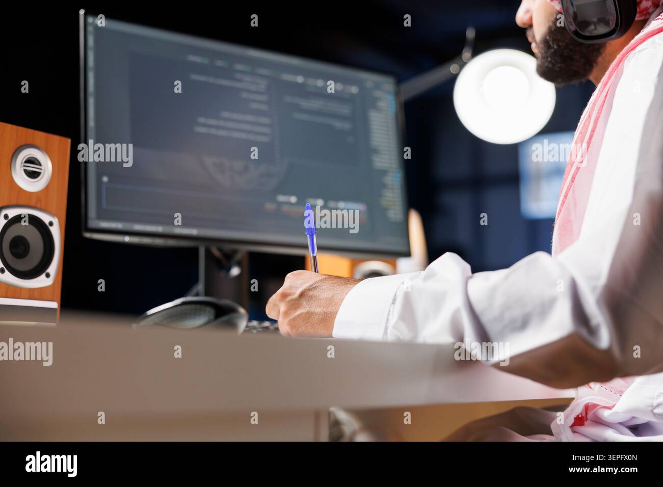 Middle Eastern software developer coding on a laptop to demonstrate the foundations of software development; while using wireless headphones, an Arab guy runs algorithms. Stock Photo