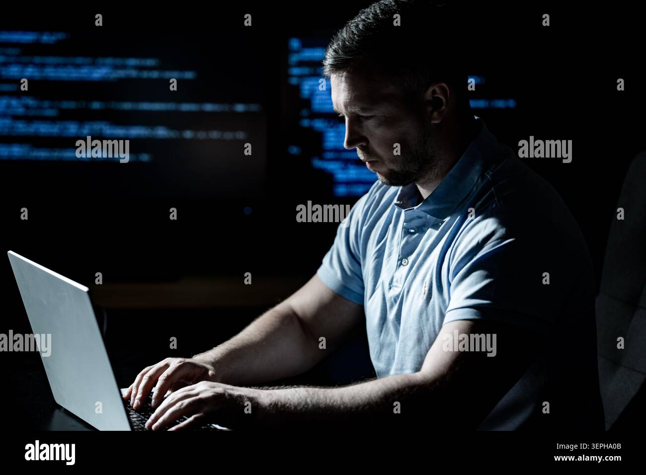 Programmer works in technology workplace. Programmer writes coding for software system. Programmer monitors network and cybersecurity threats Stock Photo