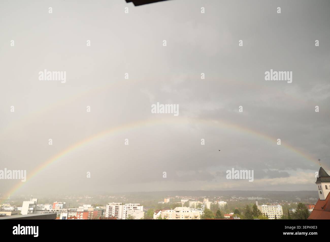 A rainbow is seen in the sky above a city Stock Photo