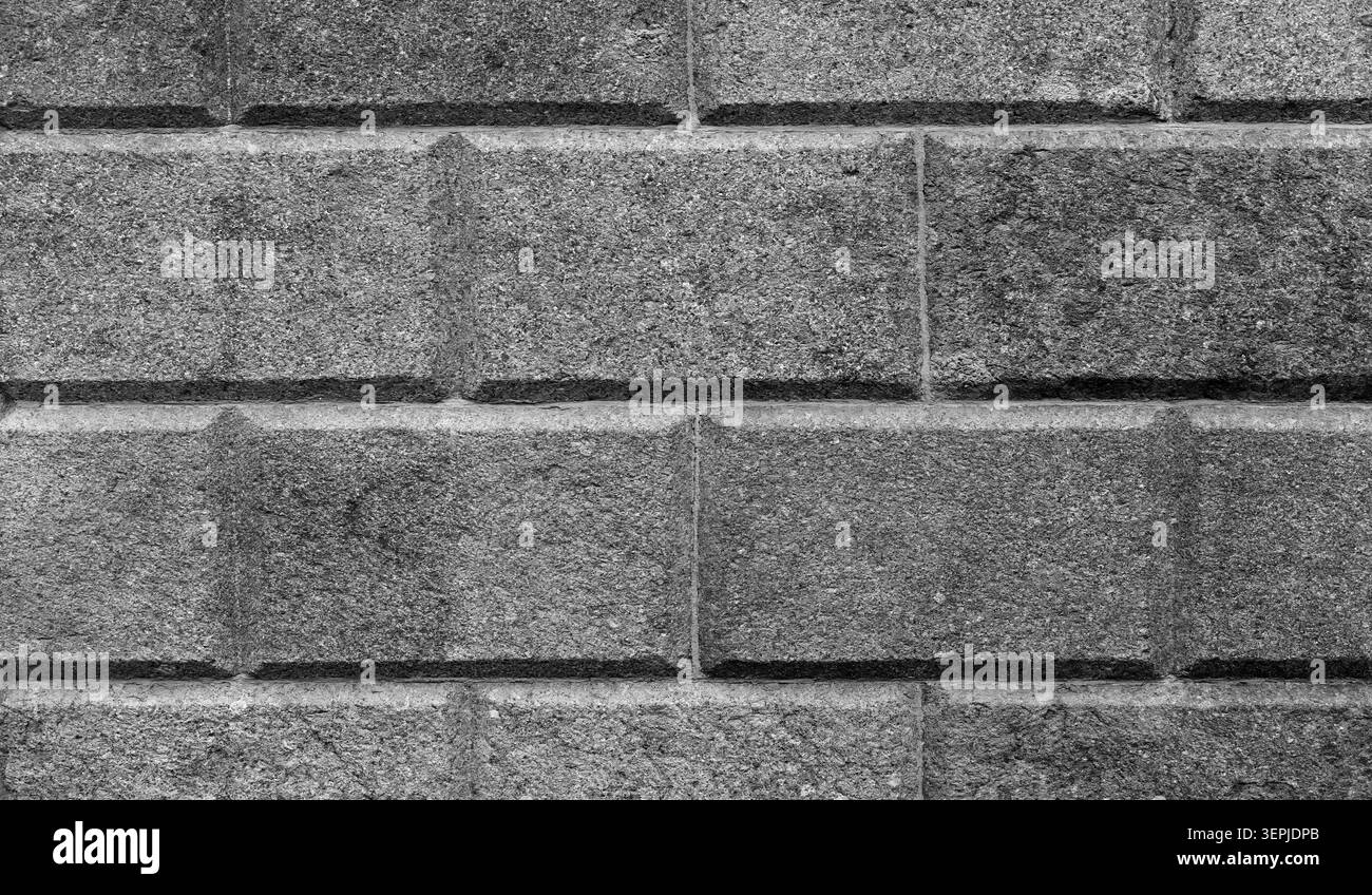 Dark gray, speckled granite block wall with beveled joints, black and white background photo texture Stock Photo