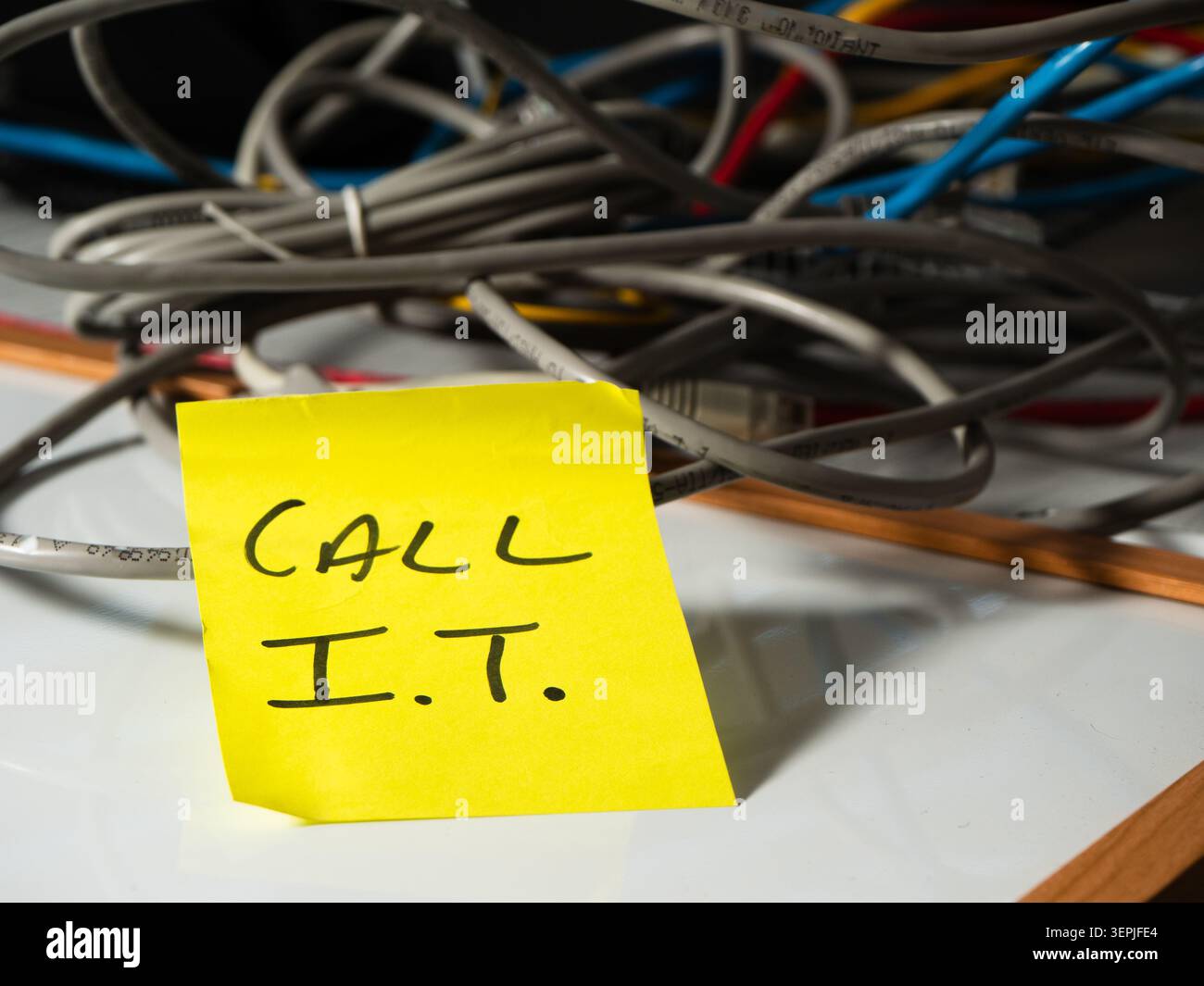 Reminder note to call network technician with messy cables background Stock Photo