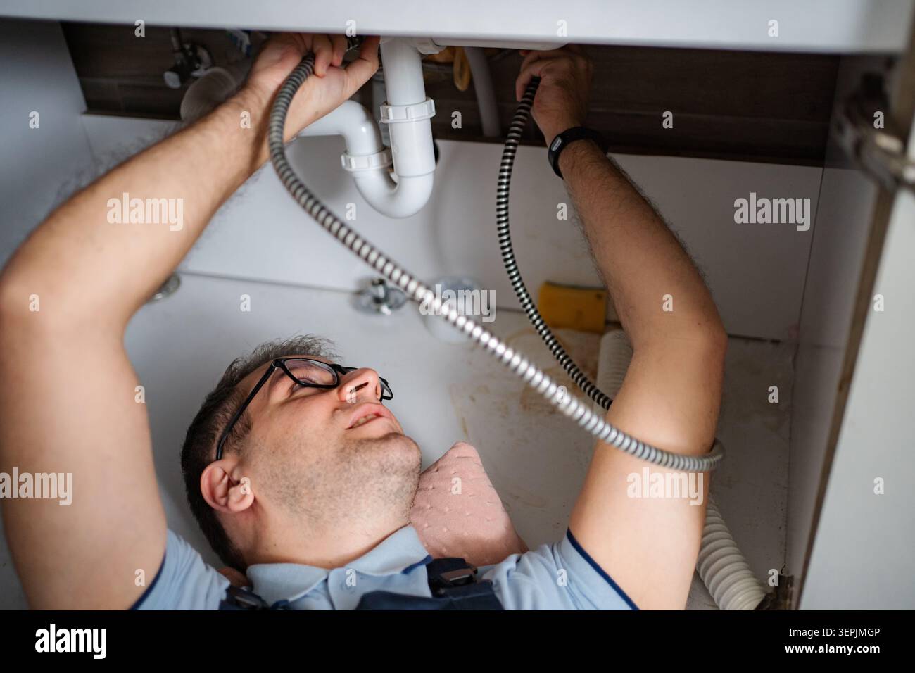Plumber working on a sink pipe blockage in kitchen Stock Photo
