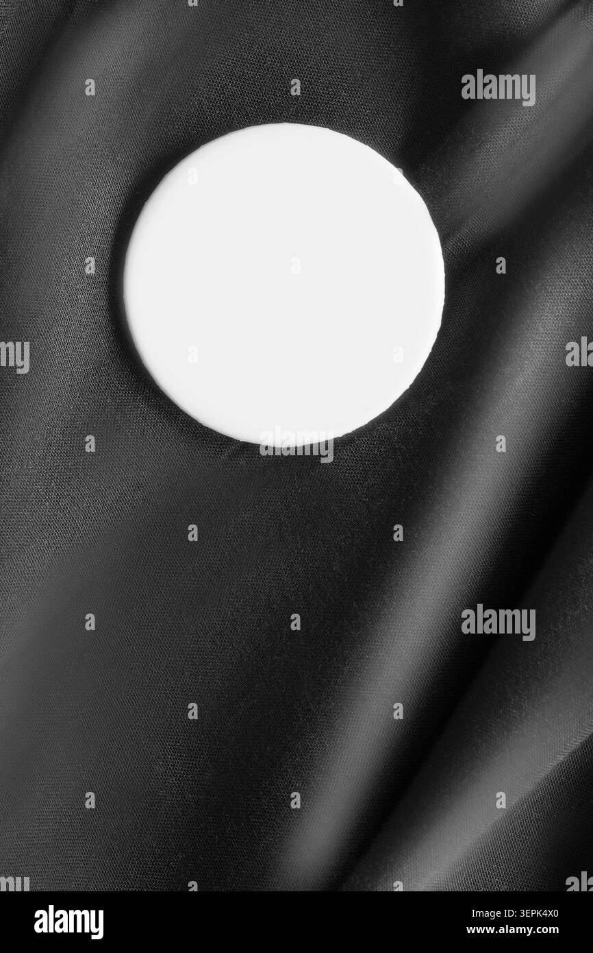 Round blank white button badge on black silk fabric background Stock Photo