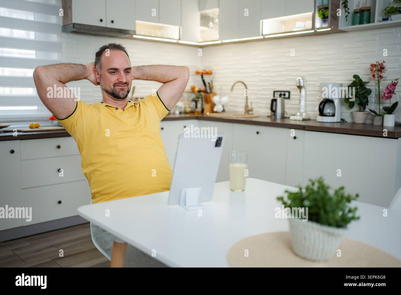 Mid adult man relaxing in kitchen using tablet Stock Photo
