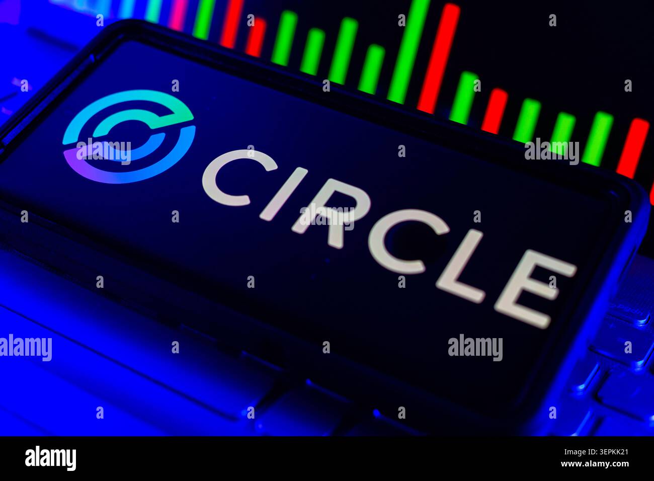 Circle Logo on Smartphone Screen With Stock Market Performance Chart on Computer Stock Photo