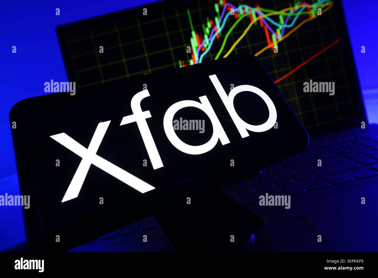 Xfab Silicon Foundries Logo on Smartphone Screen With Stock Market Performance Chart on Computer Stock Photo