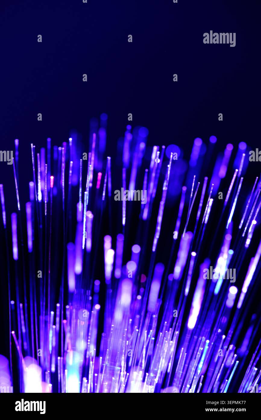 Bright purple fiber optic cables glow against dark blue background creating magic tech texture Stock Photo