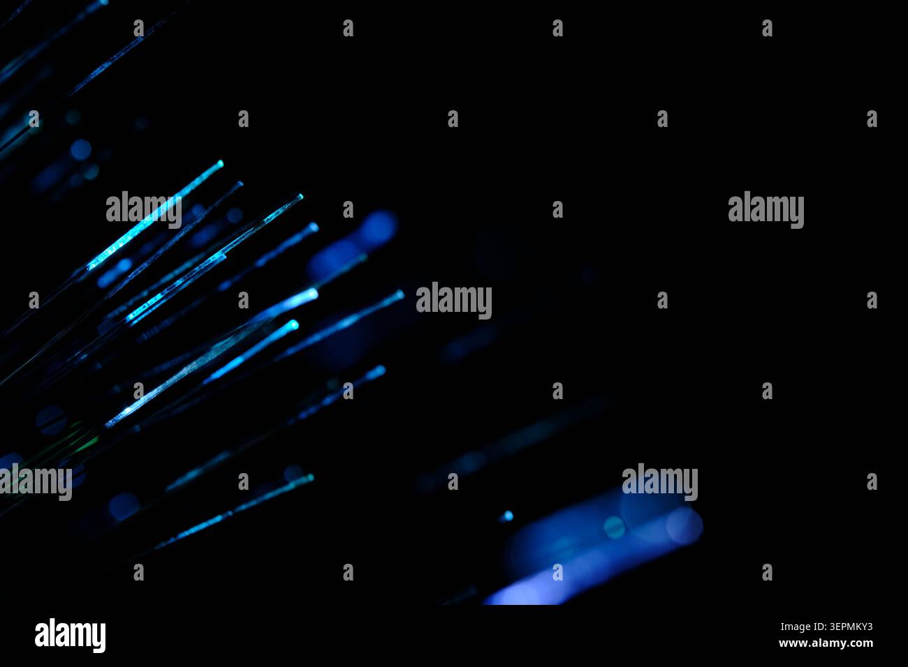 Diagonal blue and cyan glowing fiber optic strands extending out into deep dark space behind Stock Photo