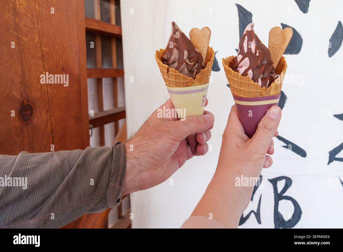 Two hands hold up soft serve milk ice cream waffle cones with chocolate Stock Photo