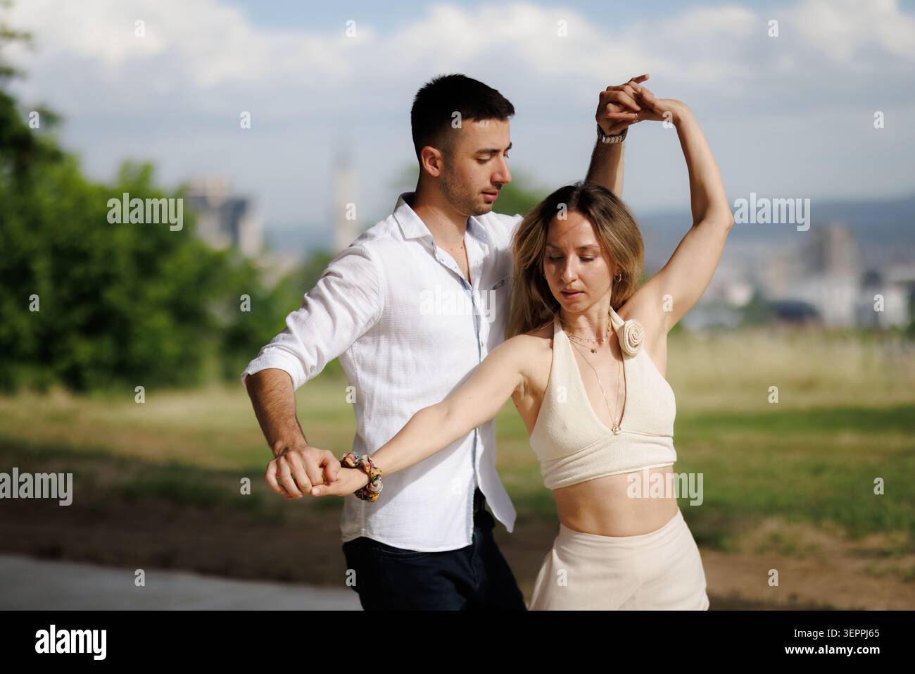 Couple dancing outdoors in a park: partners practicing a graceful partner dance with relaxed summer style and connection Stock Photo
