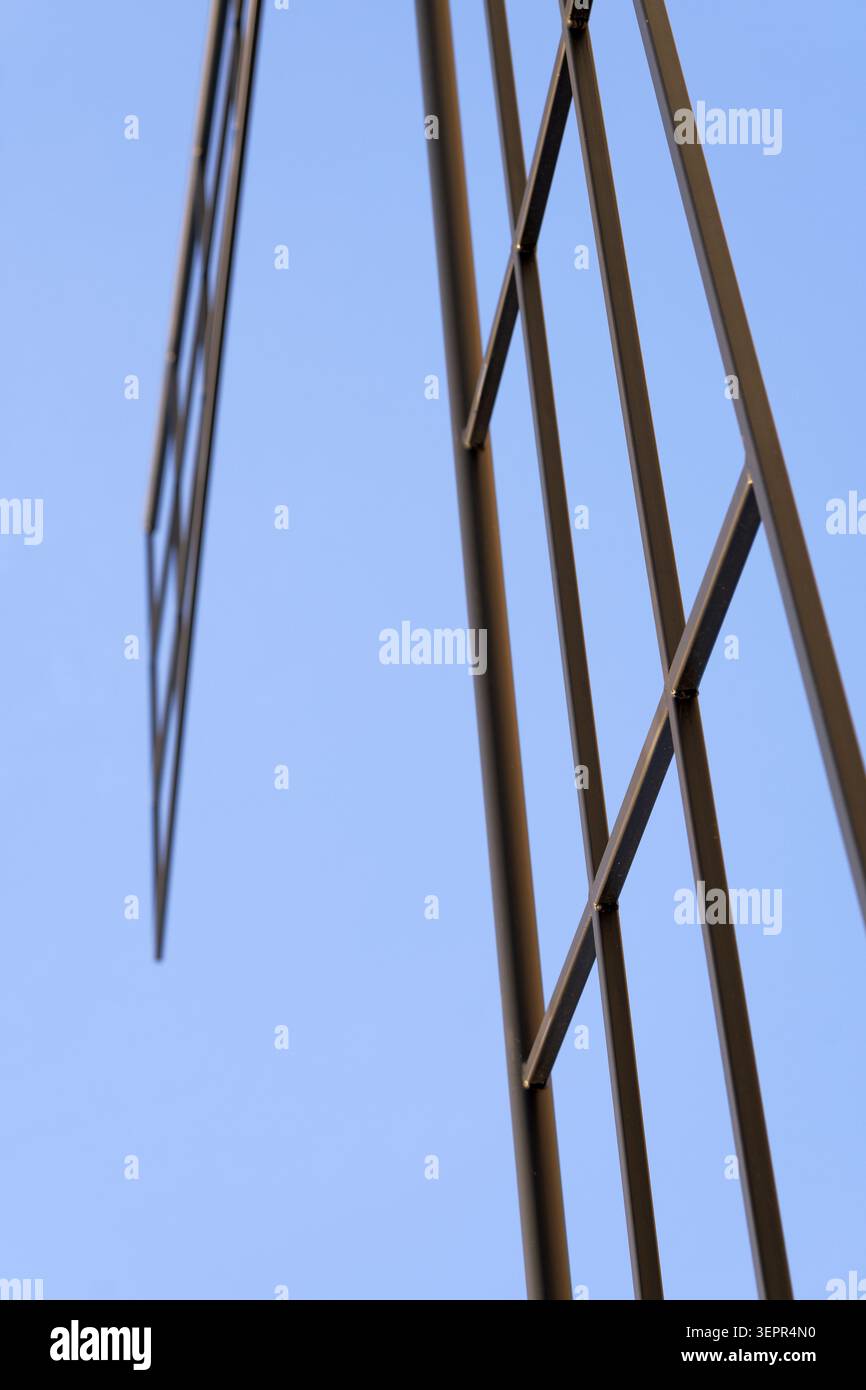 Metal framework forming an abstract geometric grid against a clear blue sky, conveying modern architecture, strength, progress and industrial design f Stock Photo