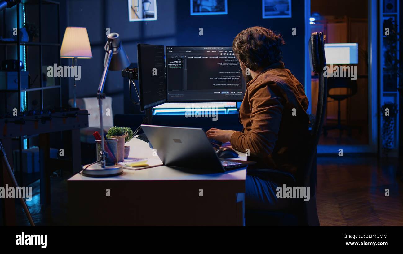 Software programmer putting headphones on while developing code, making time pass faster during remote job shift. IT professional doing multitasking in apartment office while listening music. Stock Photo