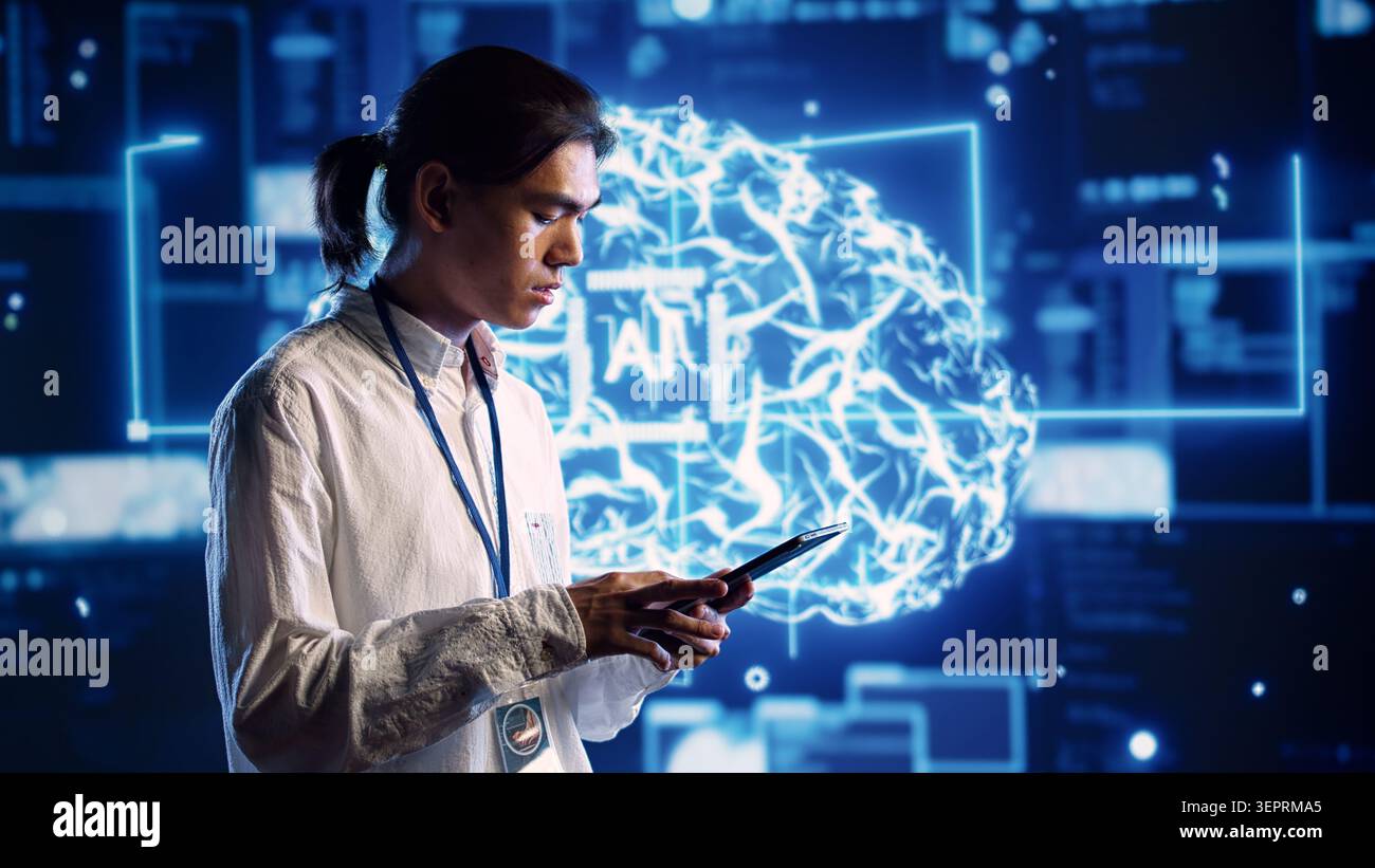 Focused technician in data center using artificial intelligence computing simulating human brain thought processes. Server room employee works on tablet with AI machine learning algorithms Stock Photo
