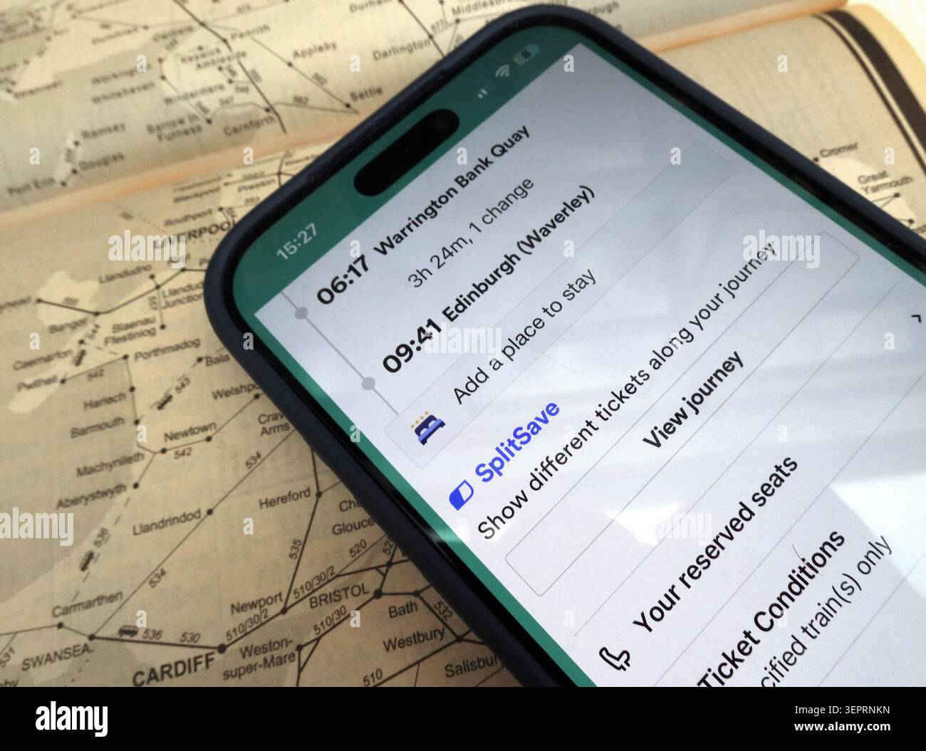 SplitSave rail ticket feature in the Trainline app displayed on an iPhone over a railway map, multiple singles for cheaper travel via the mobile app Stock Photo