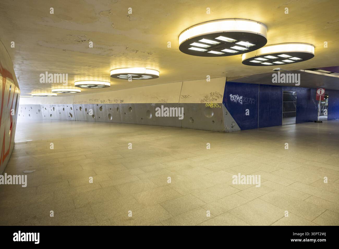Gloomy underpass on Wiener Platz in Cologne-Muelheim, characterized by cold concrete, circular wall structures and yellowish ceiling lights. The tunne Stock Photo
