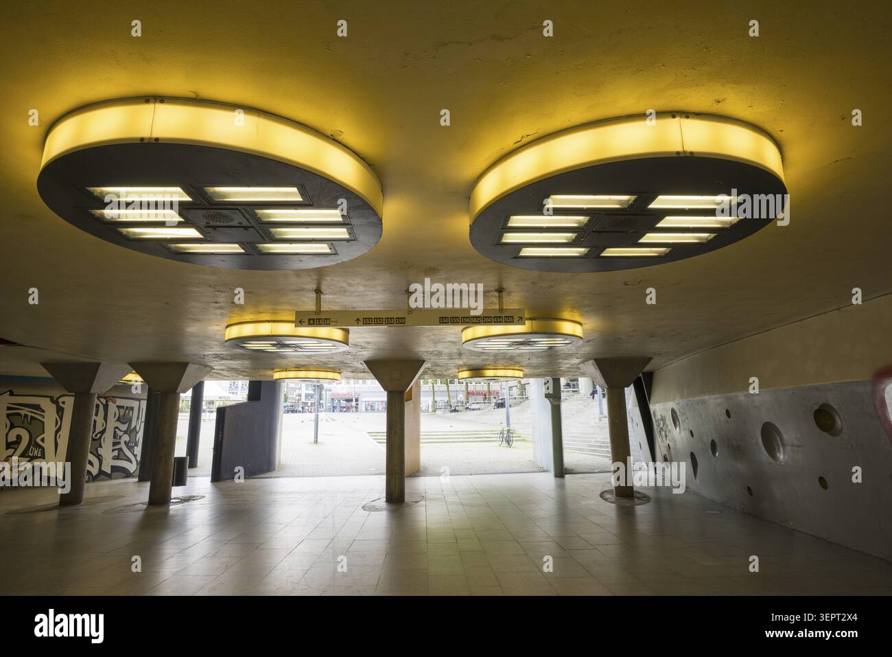 Gloomy underpass on Wiener Platz in Cologne-Muelheim, characterized by cold concrete, circular wall structures and yellowish ceiling lights. The tunne Stock Photo