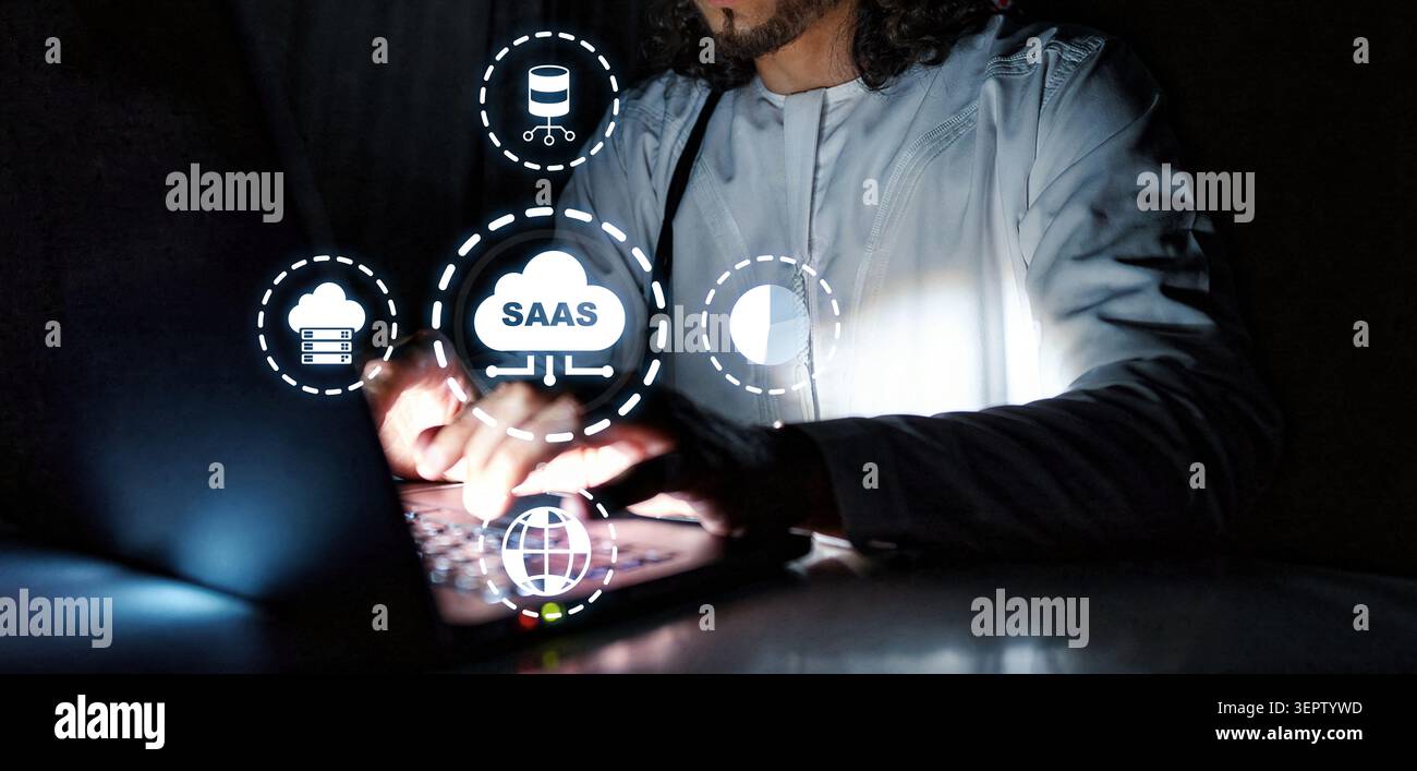 User interacts with Saas platform using laptop in a dark room at night Stock Photo