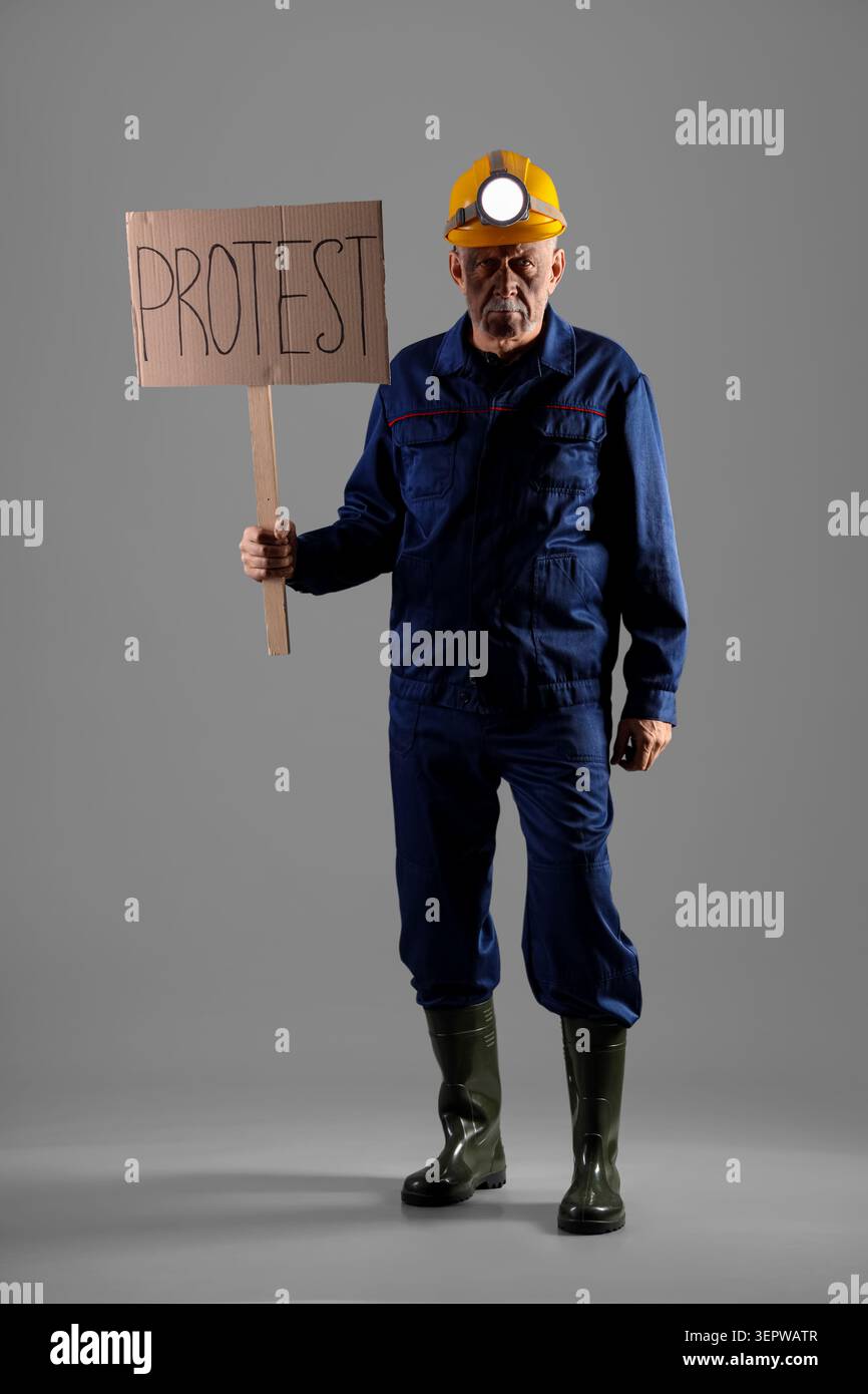 Protesting miner man with placard on grey background Stock Photo