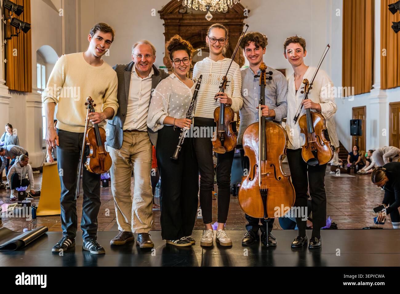 Group photograph of the Bella Musica ensemble from the Mozarteum University in Salzburg, conducted by Stefan David Hummel (second from the left, Head of Pre-College / Personal Adviser to the Rector / Co-ordinator of the International Mozart Competition / Lecturer in Orchestral Pedagogy & Ensemble), taken after the yoga event at the DomQuartier; the five musicians are holding their instruments – violins, clarinet, cello. The names of the people pictured are: Magdalena Hafner, clarinet; Norman Späth, violin; Bernadette Punisch, violin; Ruby Schieres, viola; Lenz Defregger, cello Stock Photo