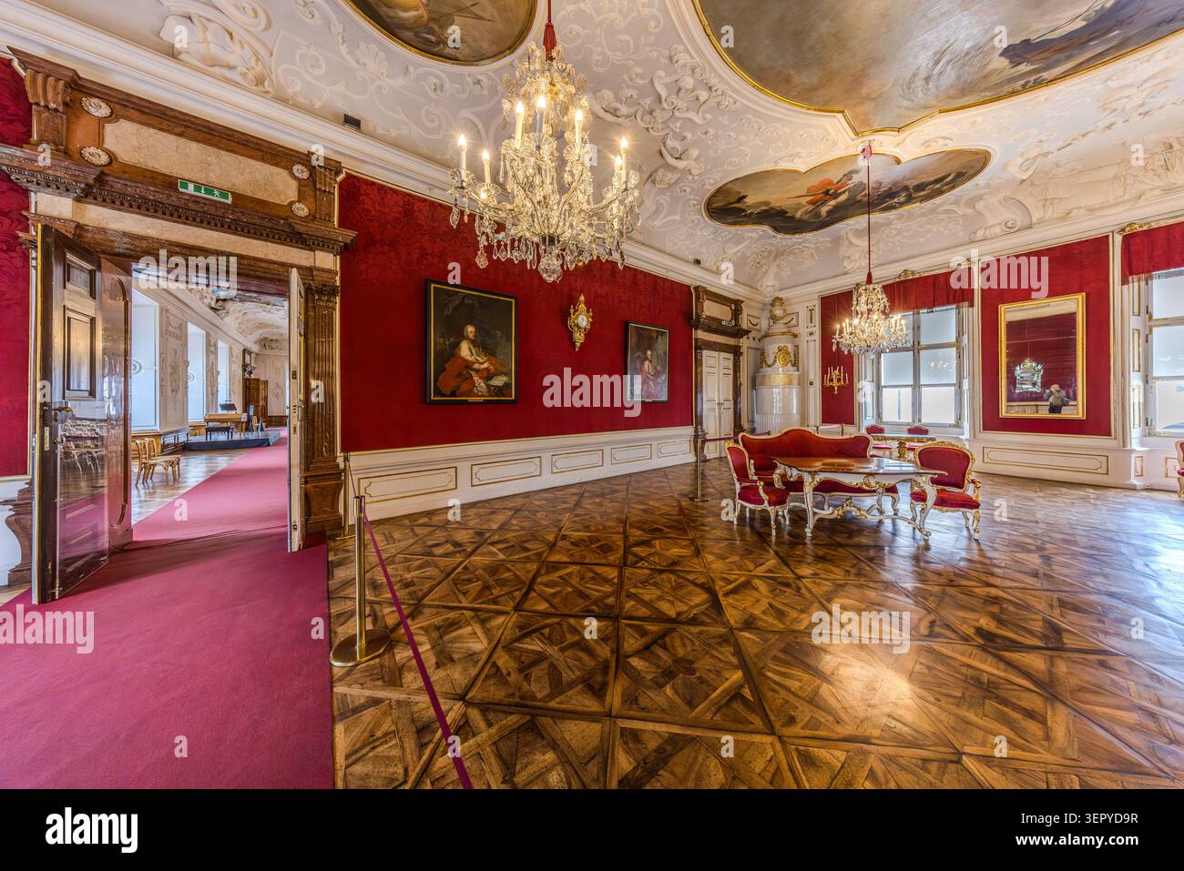 Mozart himself gave concerts in the State Room of the Archbishop’s Residence (DomQuartier Salzburg). This room, with its red damask-covered walls, inlaid parquet flooring, Rococo furniture, chandeliers and Baroque ceiling paintings, was one of the princely state rooms of the Archbishops of Salzburg, Austria Stock Photo