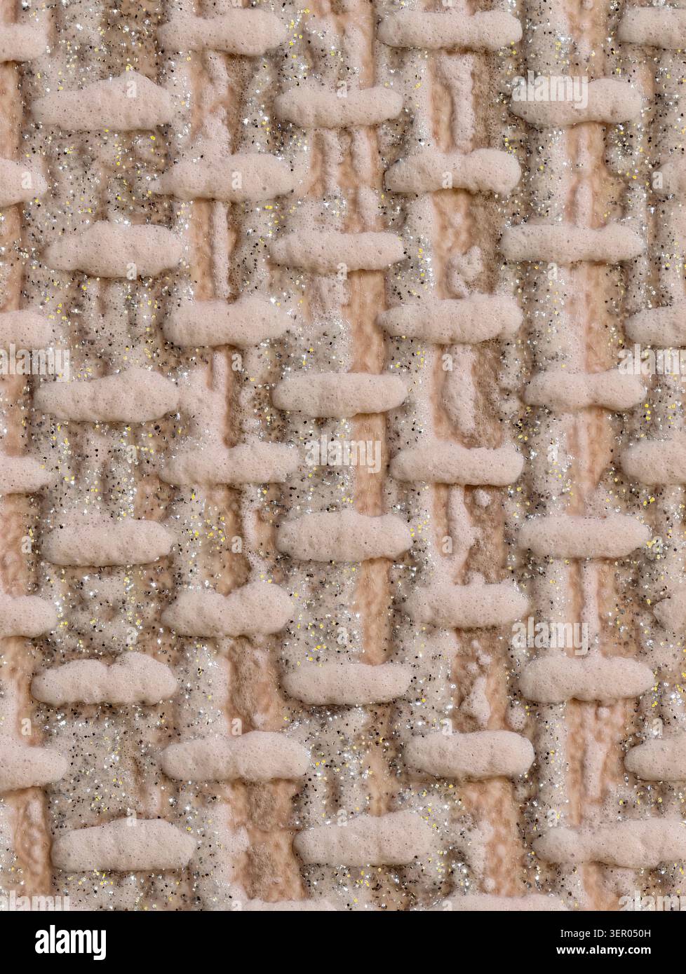 Close-up of a cream-colored woven textile featuring thick wool yarns and raised looped stitches interlaced with metallic glitter threads. The image sh Stock Photo