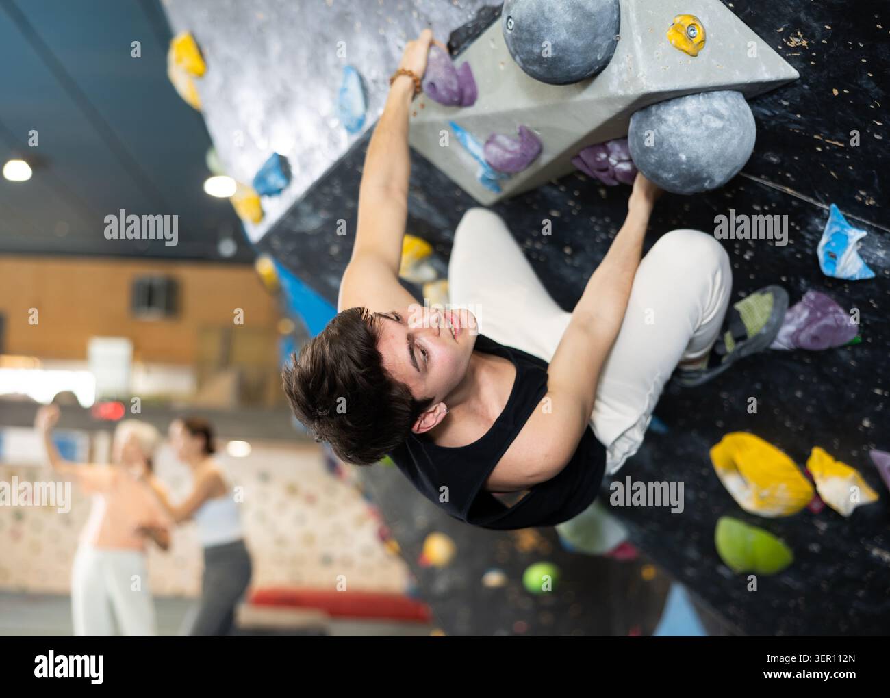 Determined young man doing his best at climbing artificial wall Stock Photo