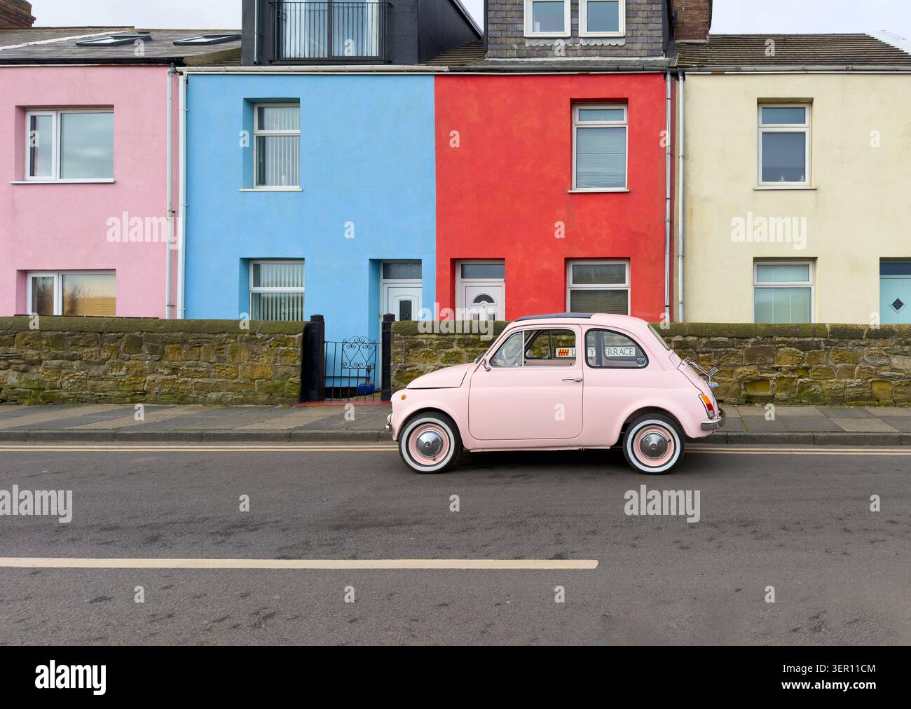 A classic pink fiat 500 parked on Unity Terrace in {{{{{next to colorful terraced houses & buildings - Smartphone Captured Stock Image