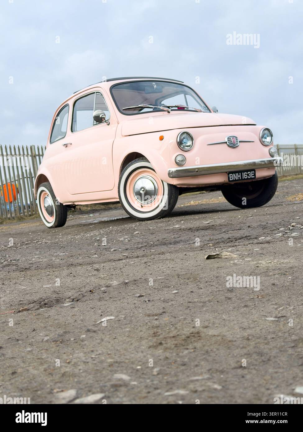Vintage pink fiat 500 parked on a dirt track in the UK - Smartphone Captured Stock Image