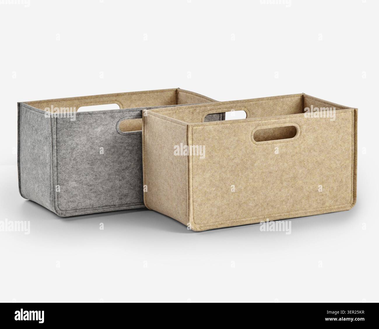 Two empty rectangular felt storage boxes in gray and beige, featuring integrated handles, ideal for organizing and decluttering Stock Photo