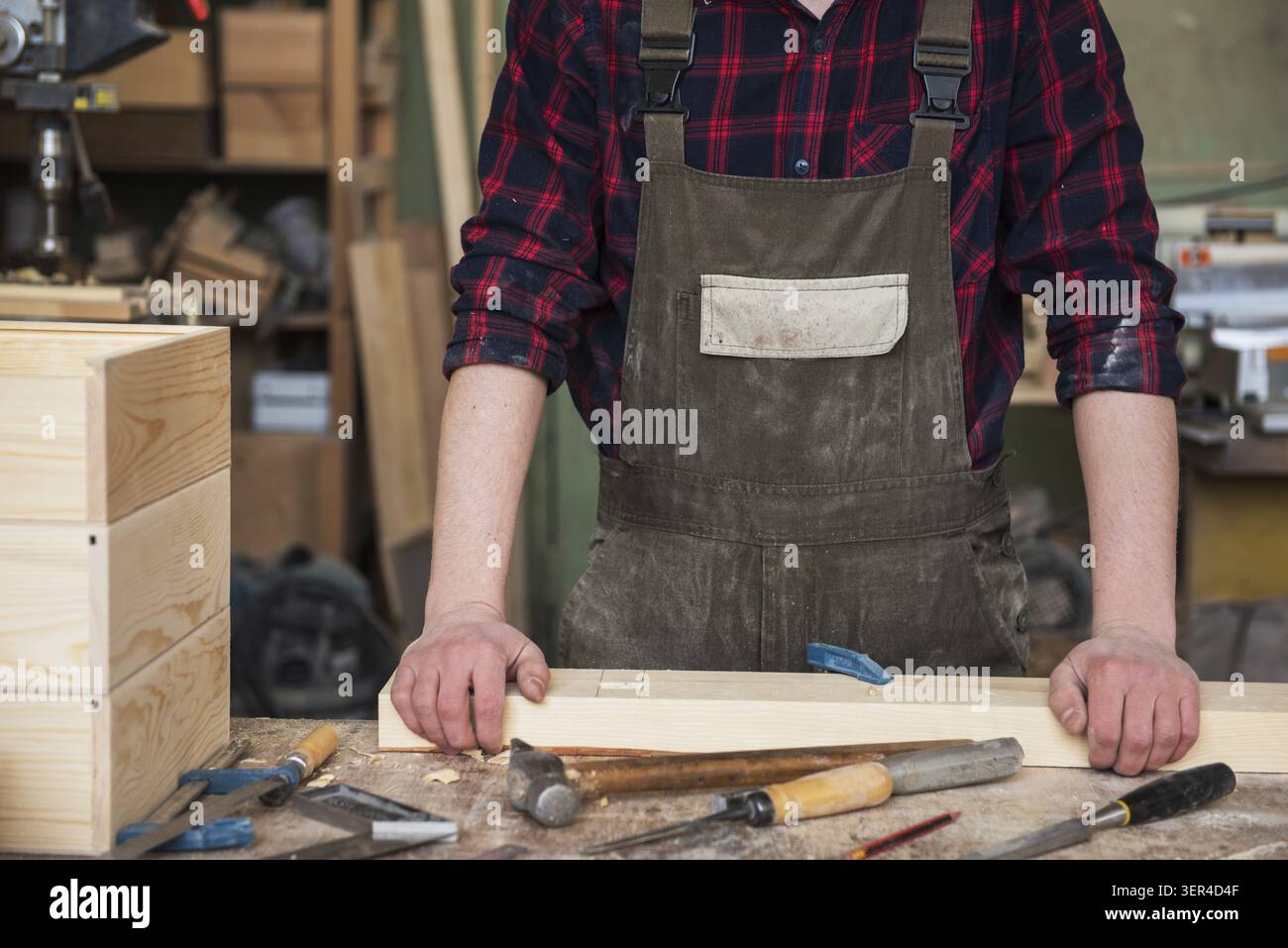 Carpenter working with a chisel and hammer in a wooden workshop Stock Photo