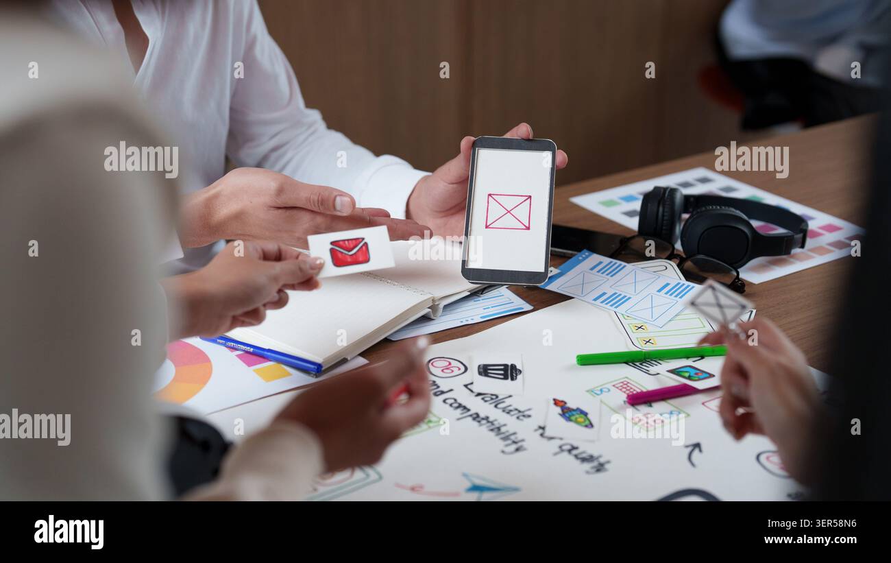 Creative design team prototyping mobile app interface with smartphone and paper mockups Stock Photo