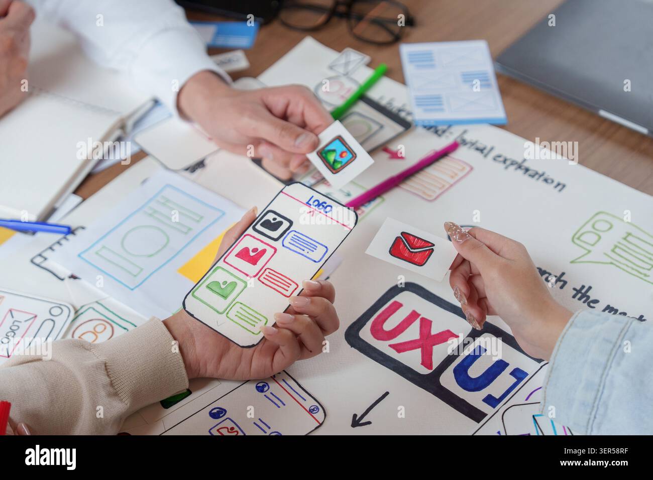 UX UI designers prototyping mobile app interface with paper wireframes Stock Photo