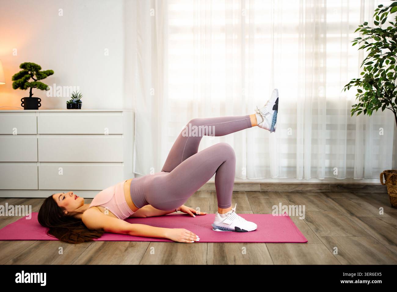 Young woman doing single leg glute bridge exercise Stock Photo