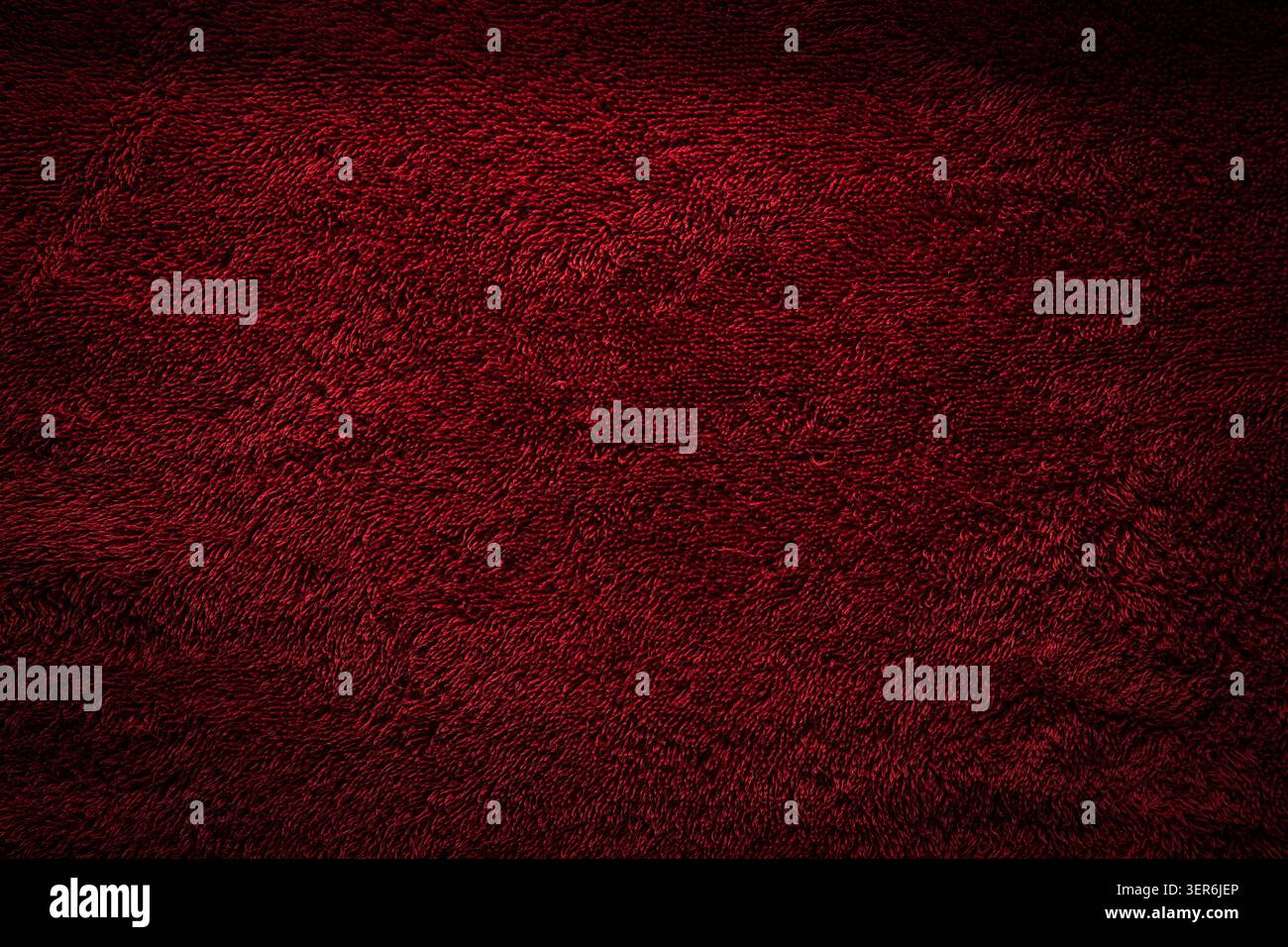 Dark red textured terry cloth background with a dramatic vignette effect. Stock Photo