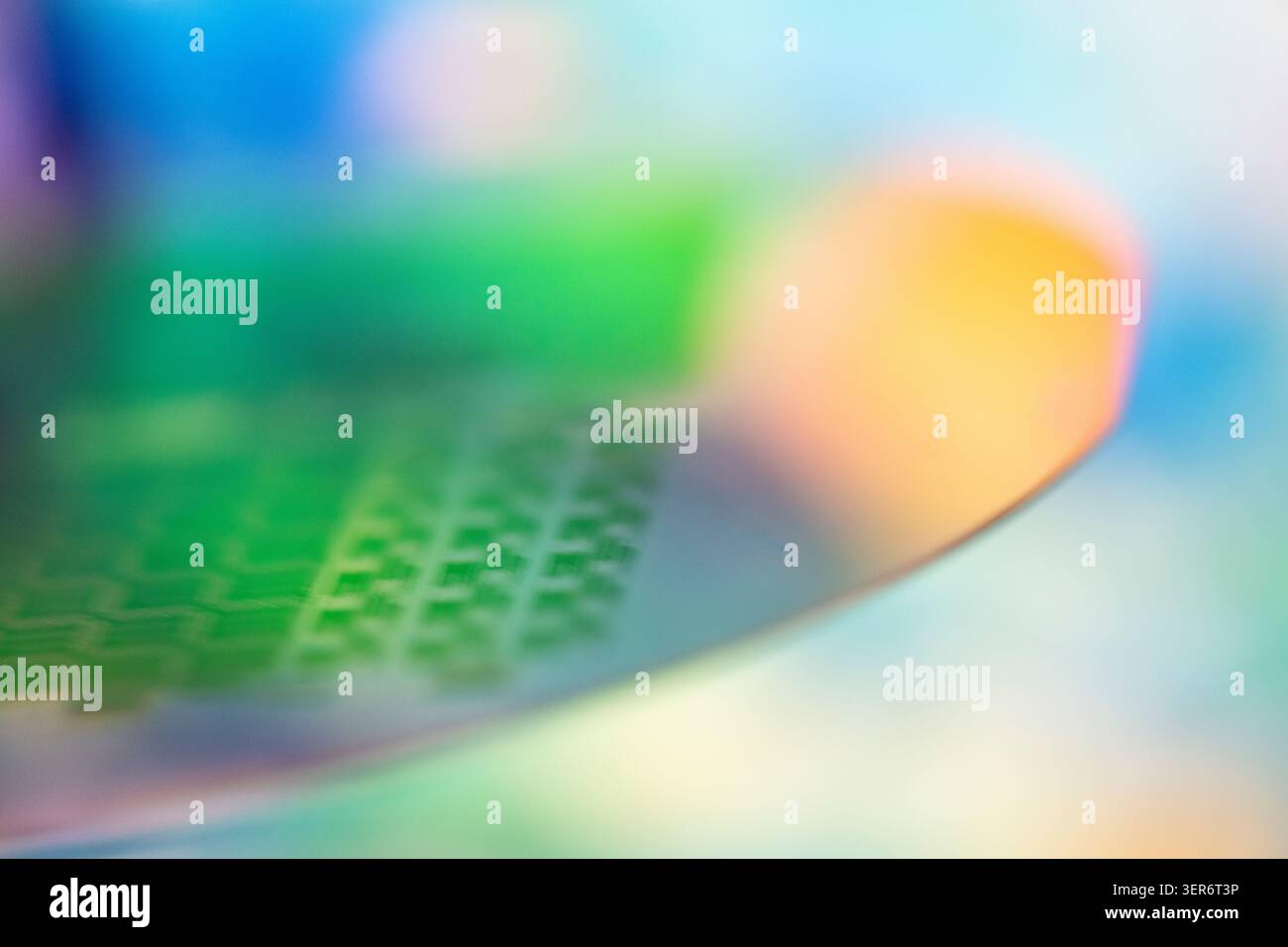 Electronic wafer showing a patterned surface with colorful blurred background Stock Photo