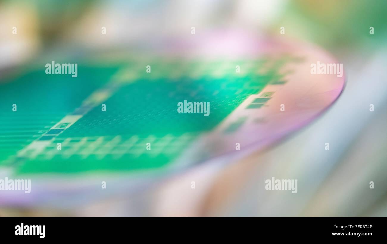 Silicon wafer reflecting light and displaying intricate electronic circuit patterns Stock Photo