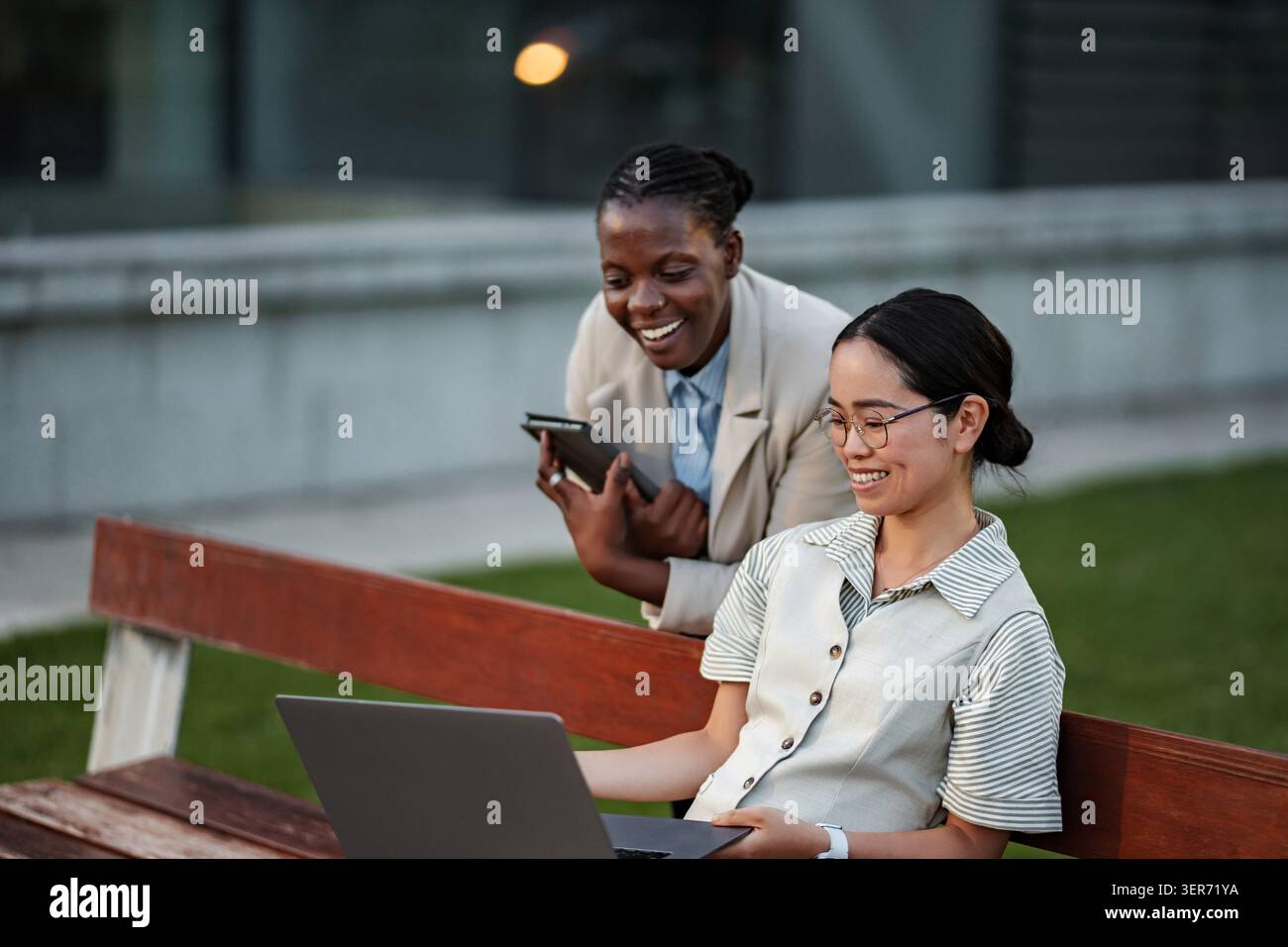 Diverse women collaborating on laptop and mobile device Stock Photo