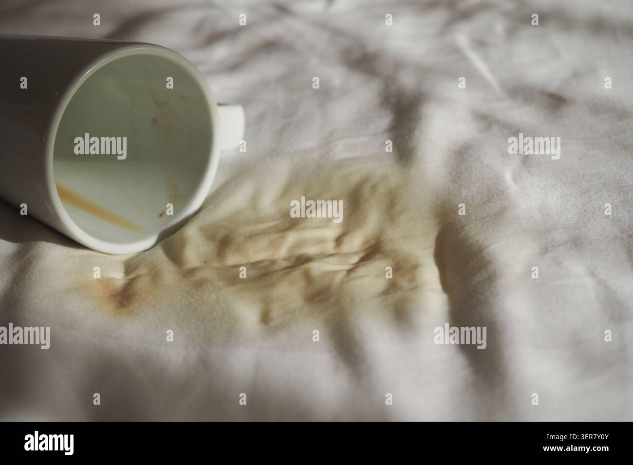 Cup spills coffee on a white tablecloth Stock Photo