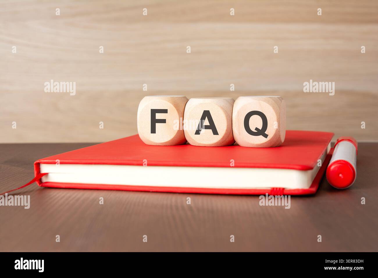 Wooden cubes with FAQ text on a red notebook Stock Photo