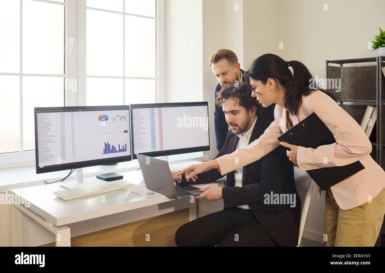 Colleagues collaborating on analytics at workstations, business data review Stock Photo
