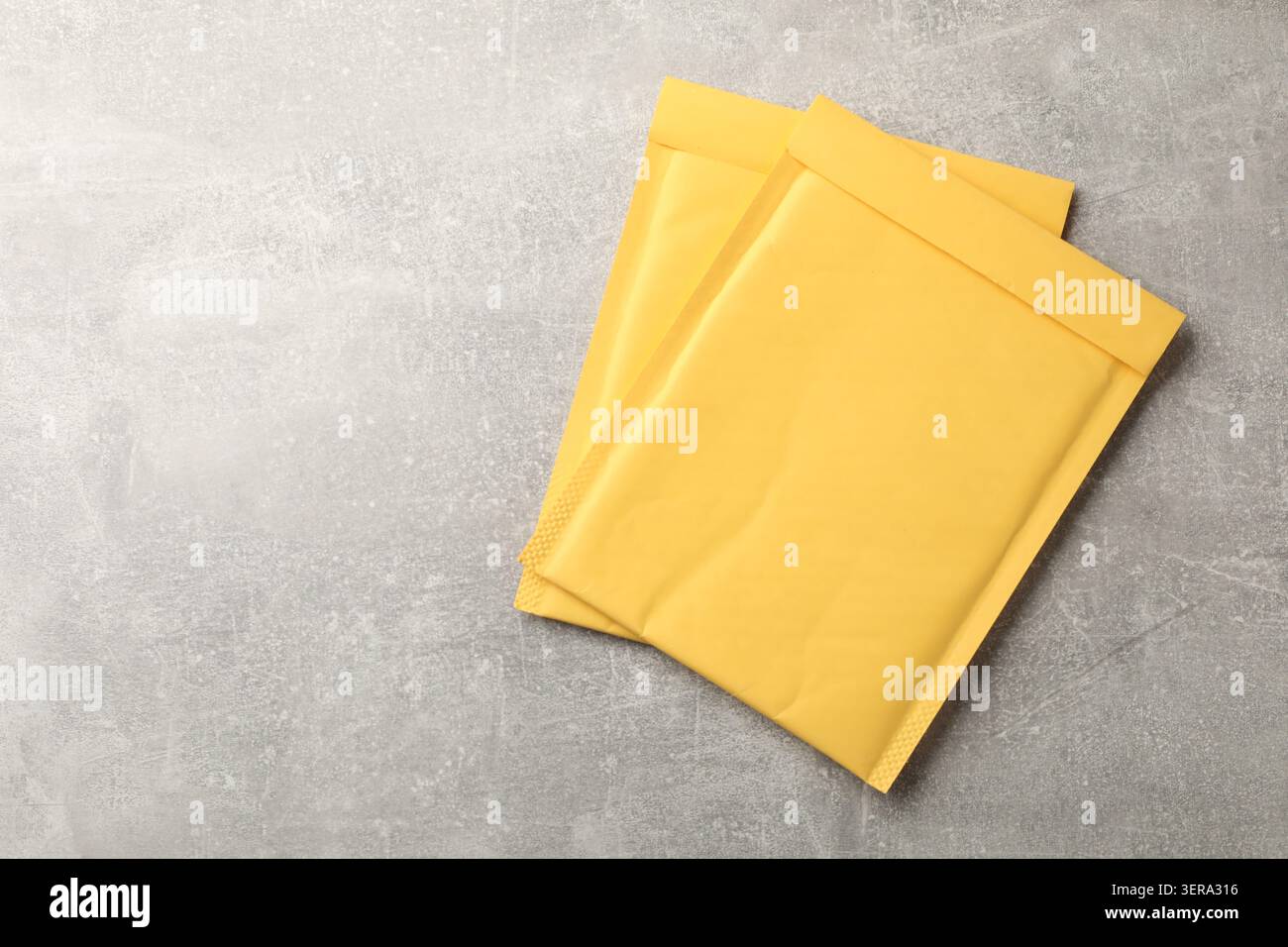 Stack of yellow envelopes on grey table, top view. Space for text Stock Photo