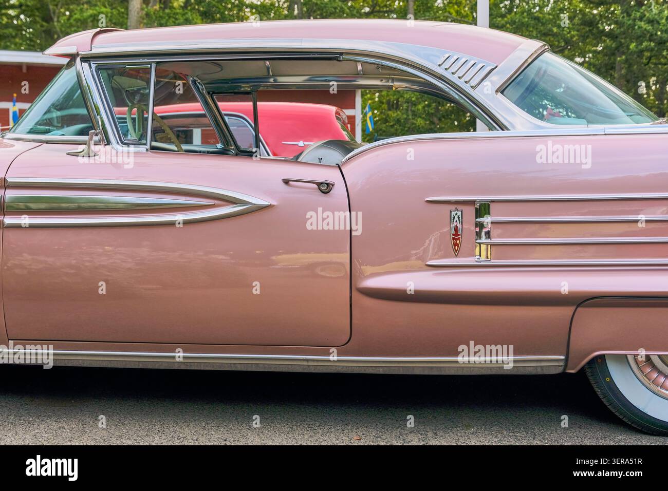 Karlskrona, Sweden - 13 September 2025: View of a vintage pink Oldsmobile with chrome accents and whitewall tires parked at Wamoparken. Stock Photo